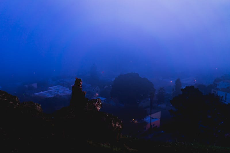 Morning fog in San Francisco with girl sitting on a cliff rock