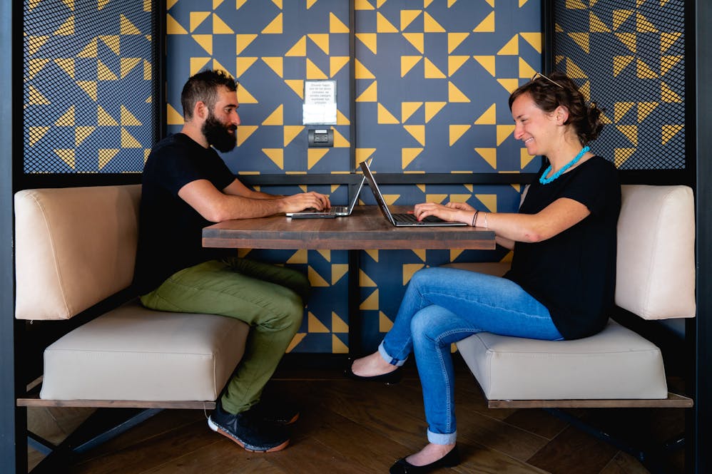 Man and women working at a shared desk in a coworking space in Medellin