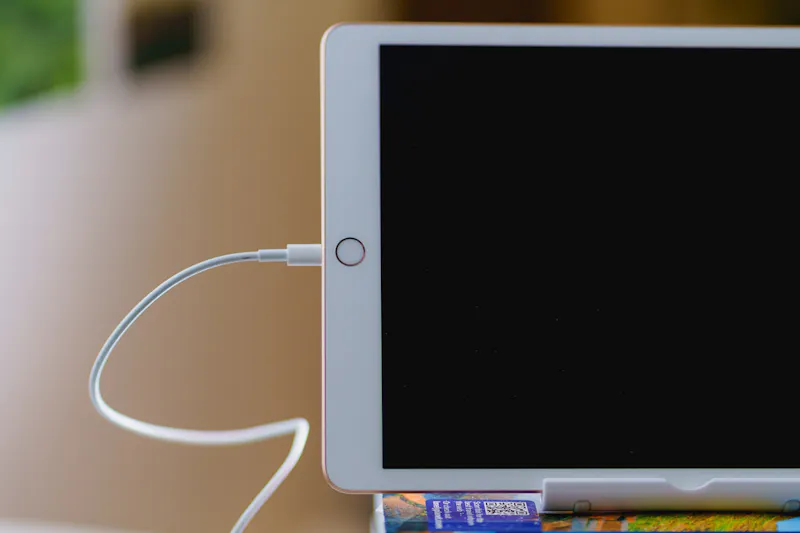 Cordon de charge branché sur un ipad blanc utilisé comme moniteur externe en tant que sidecar pour une installation de bureau à domicile